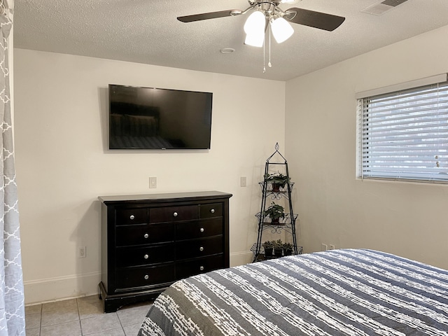 tiled bedroom with ceiling fan and a textured ceiling