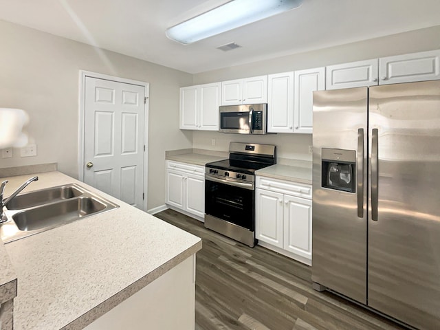 kitchen with white cabinets, stainless steel appliances, dark hardwood / wood-style floors, and sink