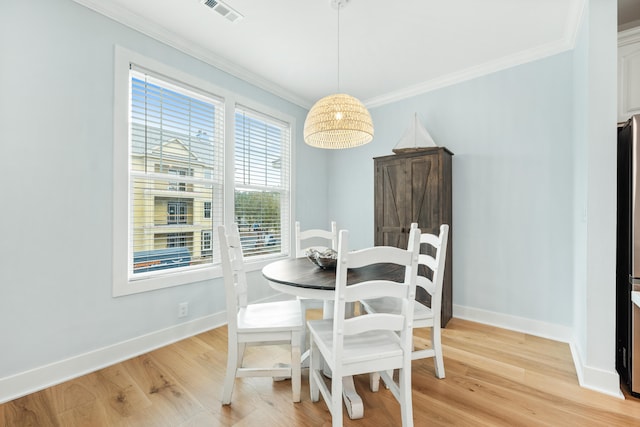 dining area featuring light wood-type flooring and crown molding