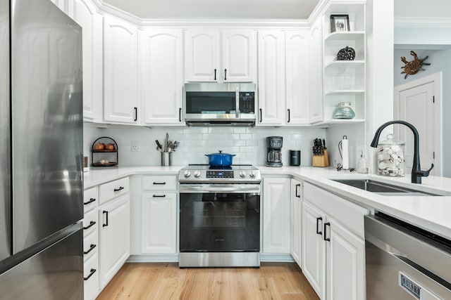 kitchen featuring white cabinetry, sink, light hardwood / wood-style floors, and appliances with stainless steel finishes