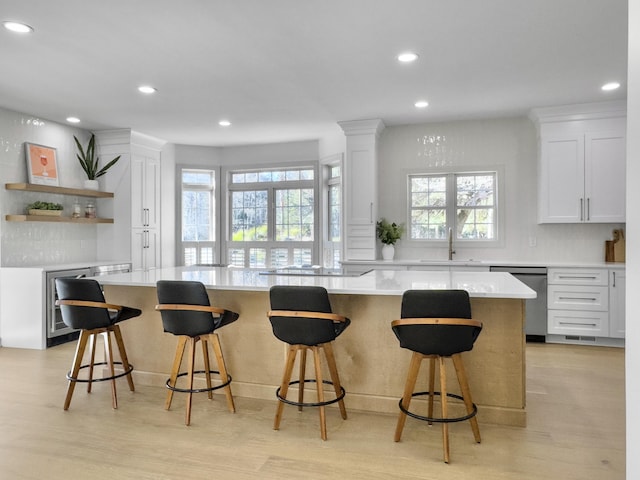 kitchen featuring a sink, white cabinetry, light countertops, light wood-type flooring, and dishwasher