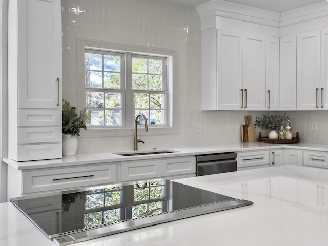 kitchen with light stone counters, a sink, white cabinets, decorative backsplash, and dishwasher