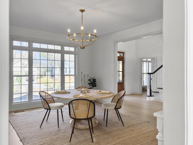 dining room with visible vents, a chandelier, light wood-type flooring, baseboards, and stairs