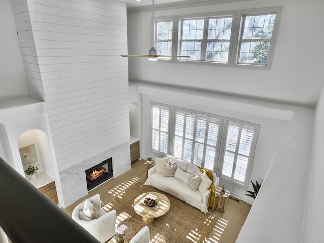 living area with a healthy amount of sunlight, a fireplace, a high ceiling, and wood finished floors