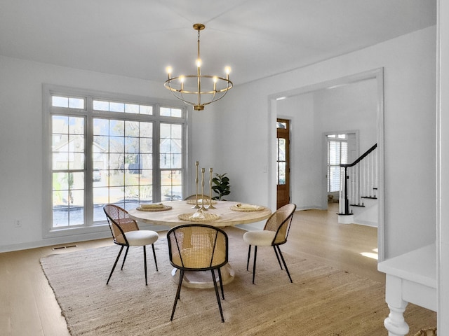 dining space featuring stairs, light wood finished floors, visible vents, and a notable chandelier