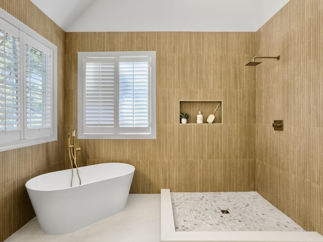 bathroom with a healthy amount of sunlight, a tile shower, a freestanding bath, and lofted ceiling