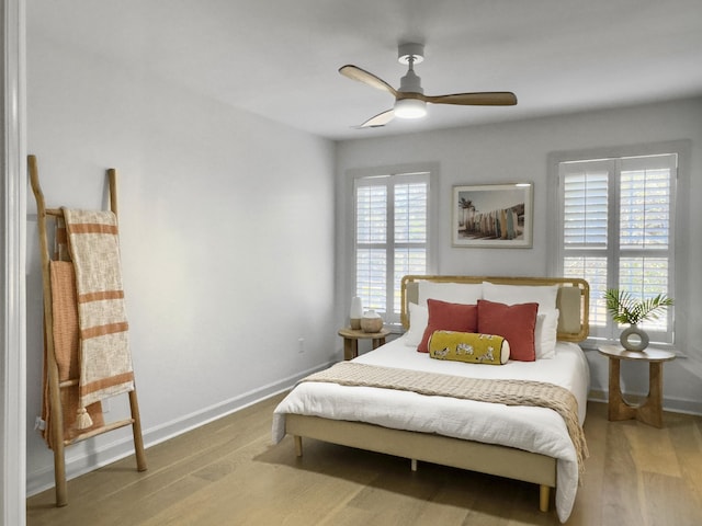 bedroom featuring ceiling fan, baseboards, and wood finished floors