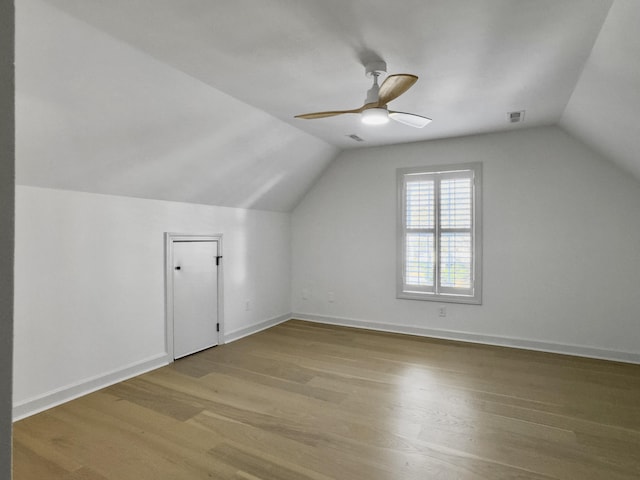 additional living space with wood finished floors, a ceiling fan, visible vents, vaulted ceiling, and baseboards