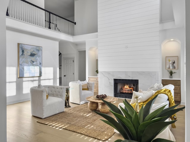 living room featuring a towering ceiling, a premium fireplace, and wood finished floors