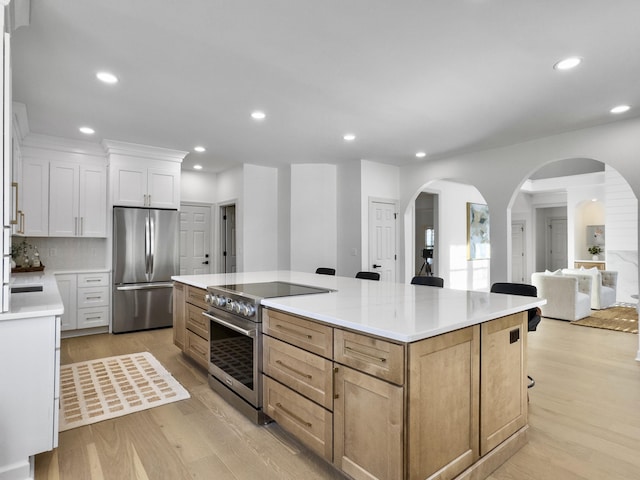 kitchen with appliances with stainless steel finishes, recessed lighting, light wood-style floors, and a spacious island