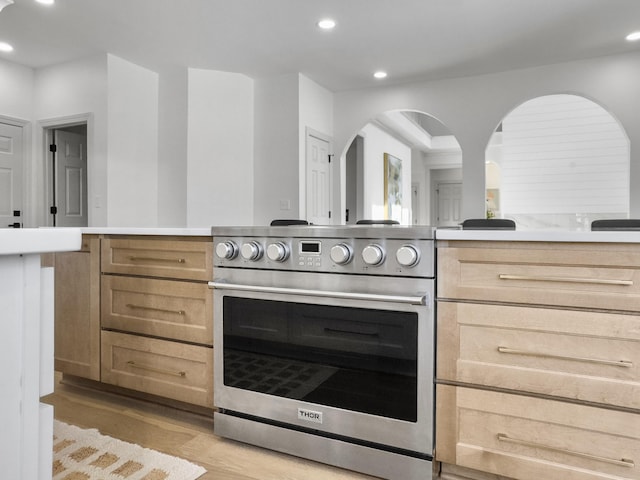 kitchen featuring light countertops, light brown cabinets, light wood-style flooring, and high end stainless steel range