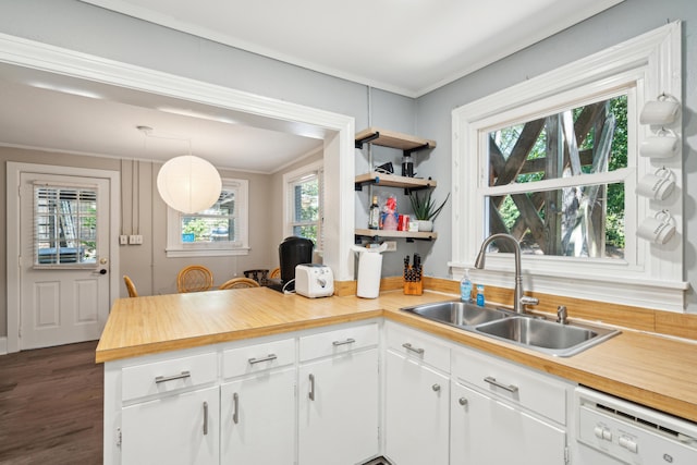 kitchen with plenty of natural light, white dishwasher, sink, decorative light fixtures, and white cabinetry