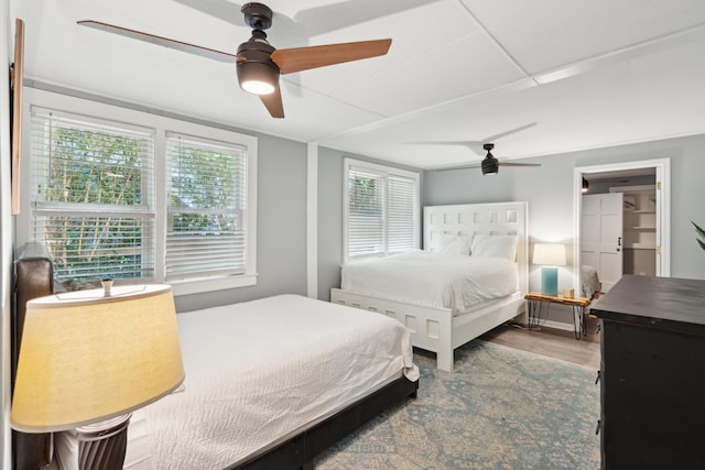 bedroom with multiple windows, wood-type flooring, and ceiling fan