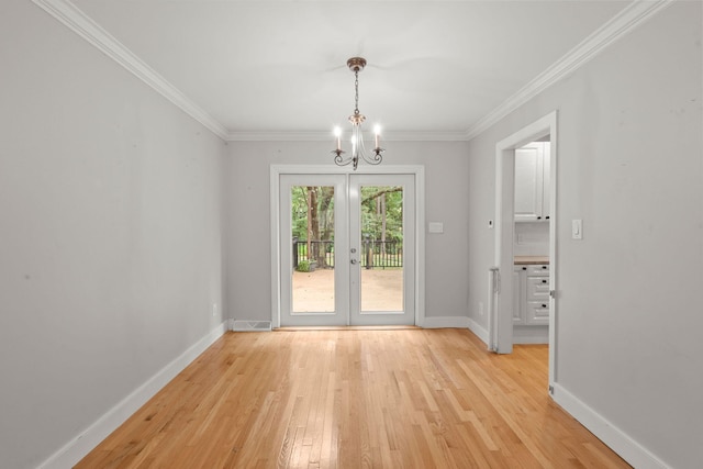 unfurnished dining area featuring ornamental molding, light wood-type flooring, a chandelier, and baseboards