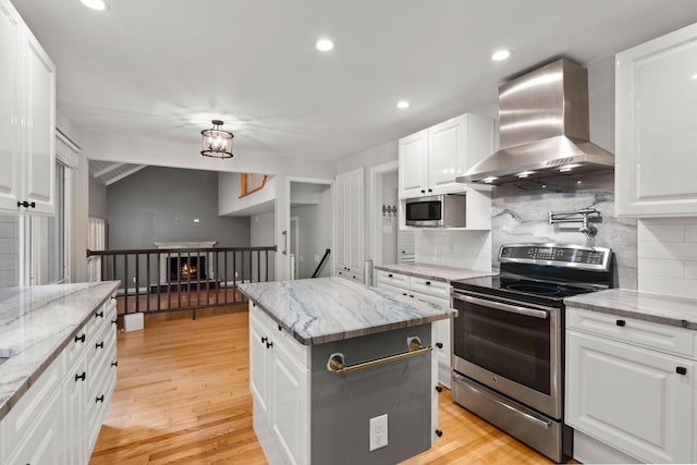 kitchen featuring stainless steel appliances, light wood finished floors, wall chimney exhaust hood, and white cabinets