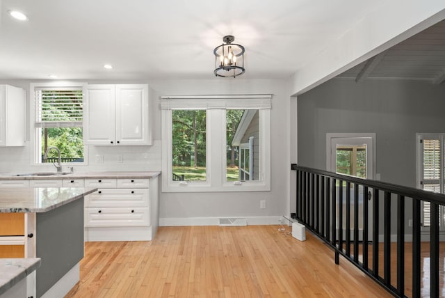 kitchen with visible vents, a sink, decorative backsplash, and white cabinetry