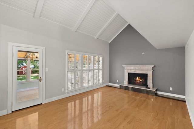 unfurnished living room featuring a premium fireplace, baseboards, wood finished floors, and beamed ceiling