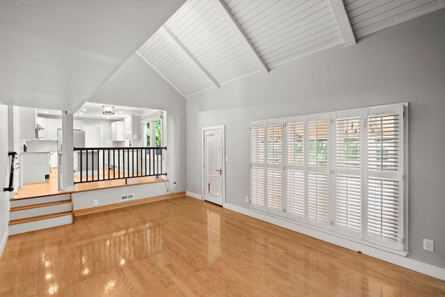 empty room with baseboards, visible vents, and beamed ceiling