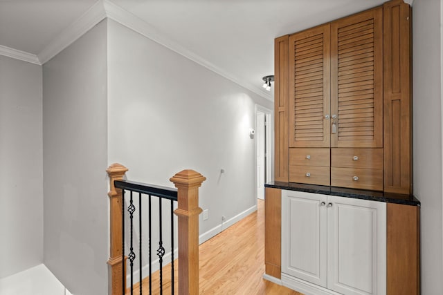 hall featuring baseboards, crown molding, light wood finished floors, and an upstairs landing