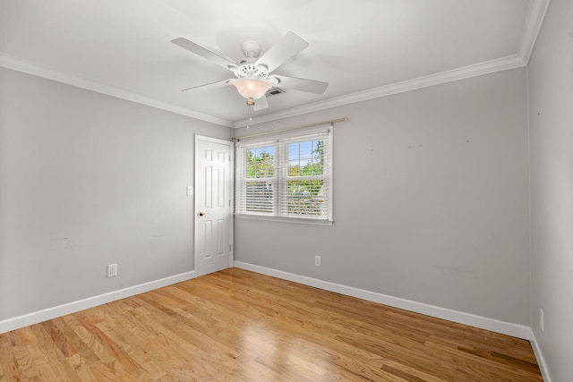 empty room with ornamental molding, light wood-style flooring, and baseboards