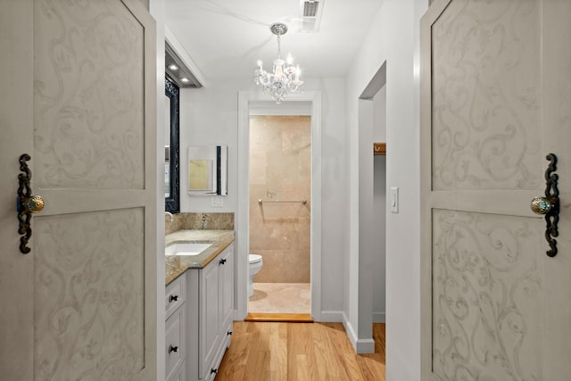 bathroom featuring baseboards, visible vents, toilet, wood finished floors, and vanity