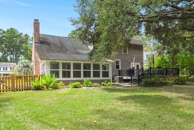 rear view of house with a deck, a yard, central AC unit, and a chimney