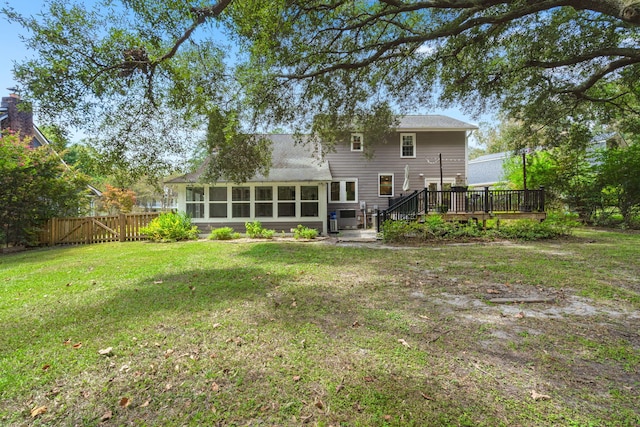 back of house featuring a yard, a wooden deck, a sunroom, and fence