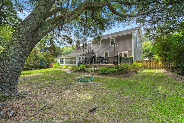 back of house with a deck, a chimney, a fenced backyard, and a lawn