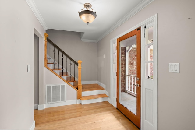 foyer with stairs, visible vents, crown molding, and wood finished floors