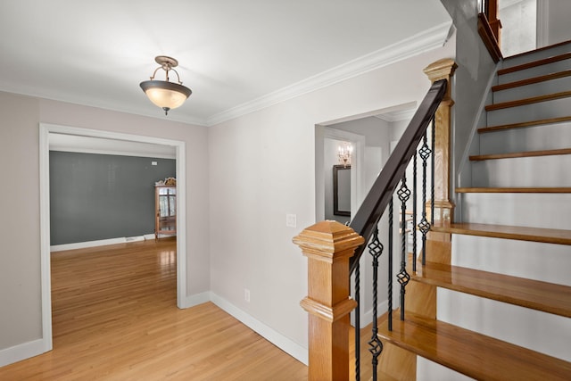 staircase with crown molding, baseboards, and wood finished floors