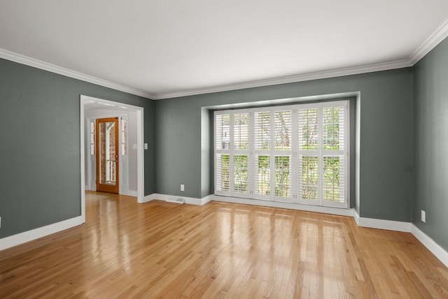 empty room with ornamental molding, baseboards, and light wood finished floors