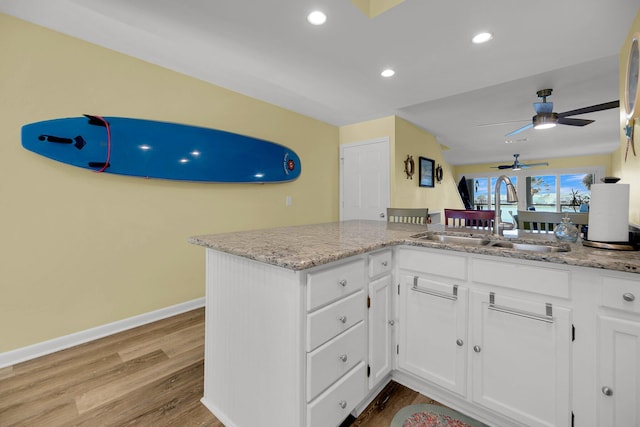 kitchen featuring white cabinetry, sink, light hardwood / wood-style floors, and kitchen peninsula