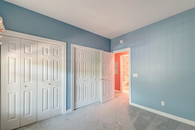 unfurnished bedroom with light carpet and multiple closets