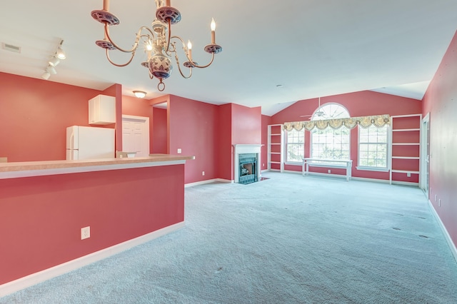 unfurnished living room with a notable chandelier, lofted ceiling, light colored carpet, and rail lighting