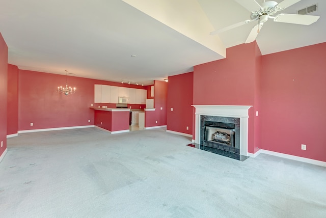 unfurnished living room featuring light colored carpet, ceiling fan with notable chandelier, and a high end fireplace