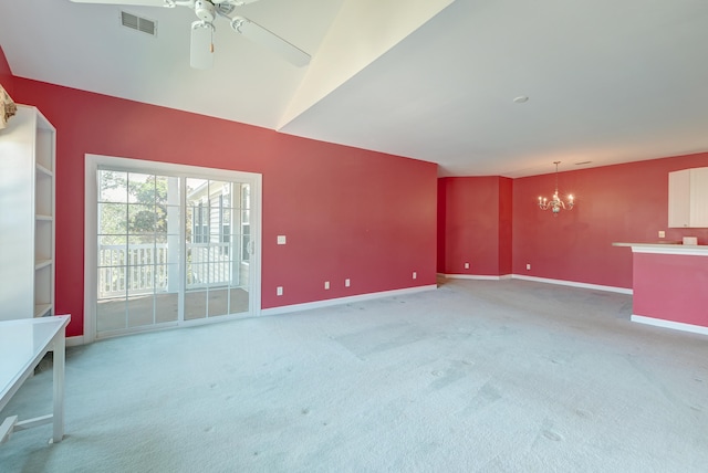 unfurnished living room with carpet, ceiling fan with notable chandelier, and vaulted ceiling