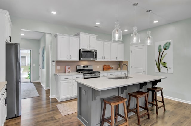 kitchen with appliances with stainless steel finishes, white cabinetry, a kitchen island with sink, and sink