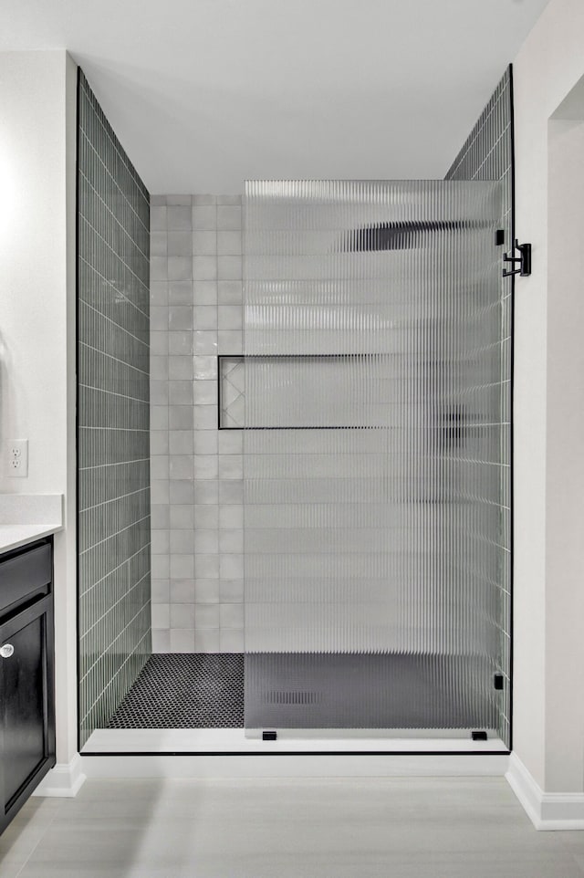 bathroom with a tile shower and vanity