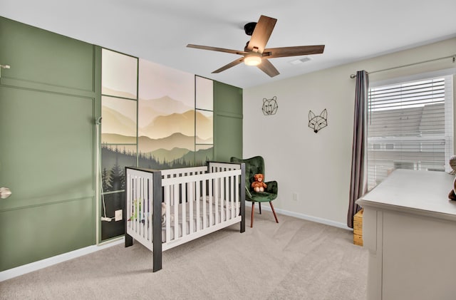 bedroom with ceiling fan, light colored carpet, and a crib