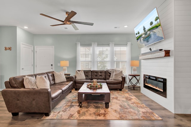 living room featuring ceiling fan, a fireplace, and hardwood / wood-style flooring