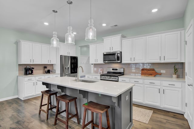 kitchen with sink, white cabinets, stainless steel appliances, and decorative light fixtures