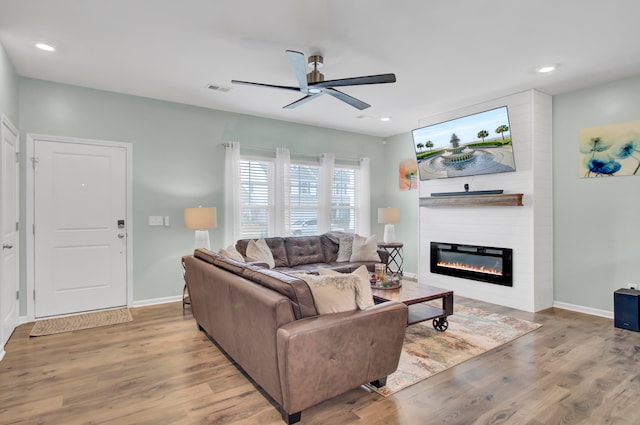 living room featuring a fireplace, light hardwood / wood-style floors, and ceiling fan