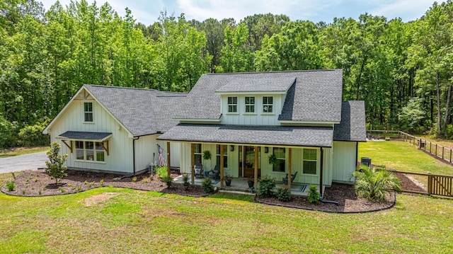 view of front of house featuring a shingled roof, a porch, board and batten siding, and a wooded view