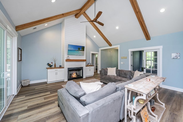 living area with beam ceiling, wood finished floors, a large fireplace, recessed lighting, and baseboards