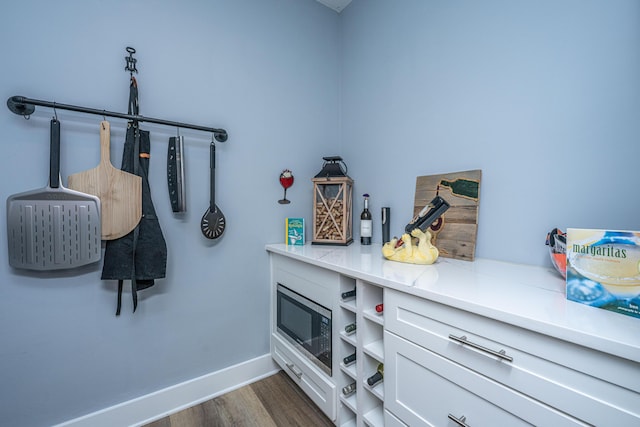 interior space featuring baseboards, wood finished floors, and stainless steel microwave