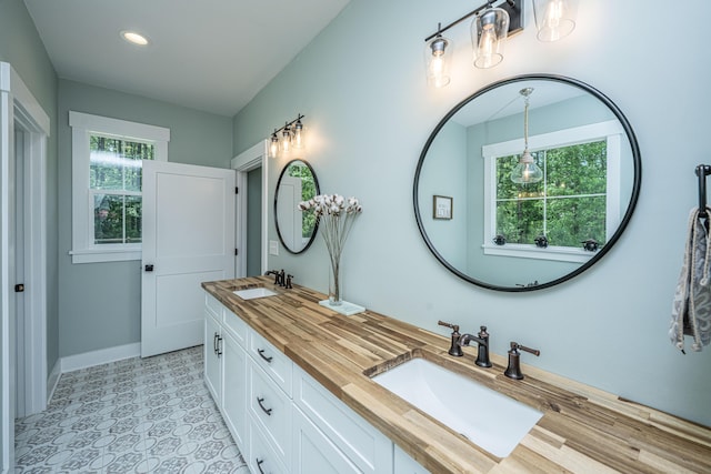 full bath with baseboards, double vanity, and recessed lighting