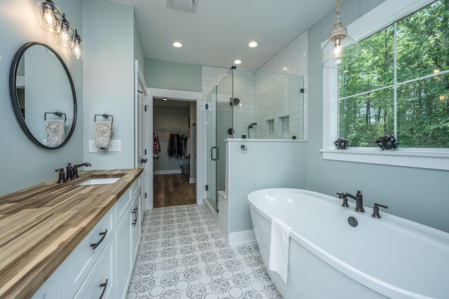 bathroom with a shower stall, a walk in closet, vanity, a soaking tub, and recessed lighting
