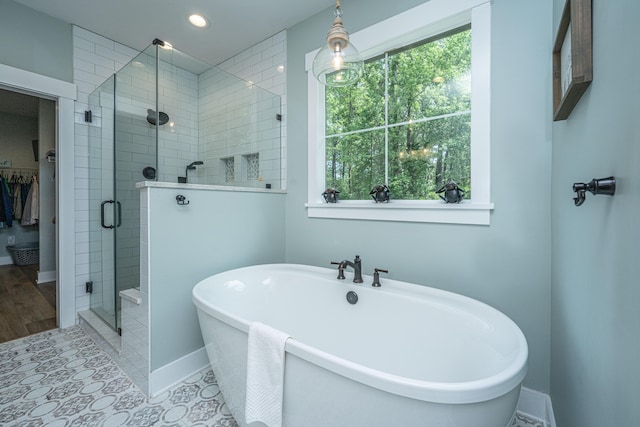 full bathroom with a shower stall, a soaking tub, healthy amount of natural light, recessed lighting, and baseboards