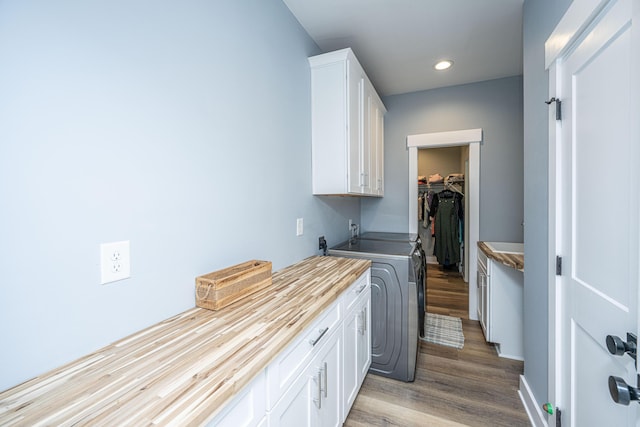 laundry area with cabinet space, wood finished floors, and recessed lighting