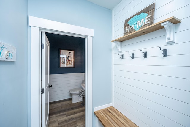 bathroom featuring toilet, wood finished floors, and wood walls